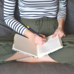 Ragazza che scrive su un diario facendo journaling a casa sul divano