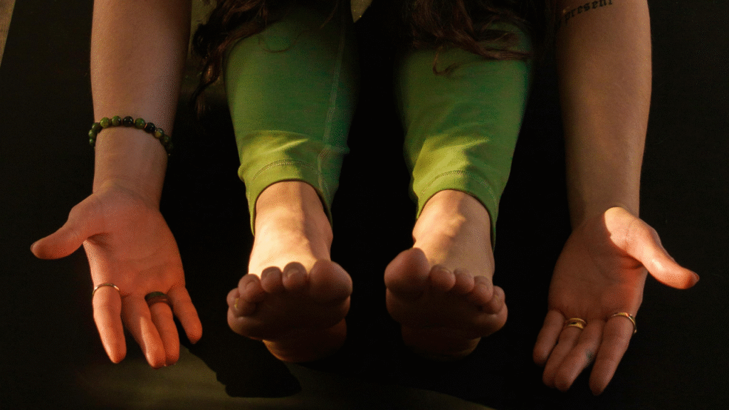 donna sul tappetino nella posizione della pinza con mani e piedi in contatto con la terra in cerca di radicamento